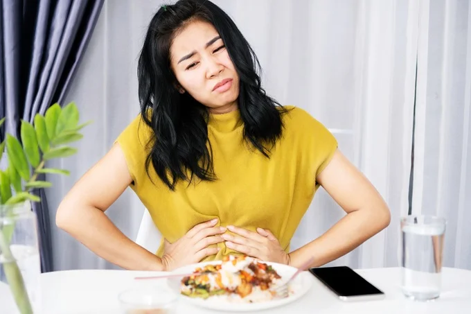 woman suffering with stomach pain Eating heavy or rich meals can trigger acid reflux.